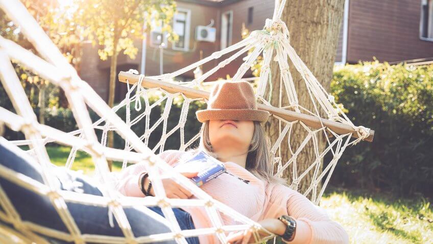 Young woman lying down and sleeping on a hammock.