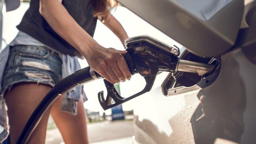Unrecognizable woman filling a gas tank of her car at gas station.