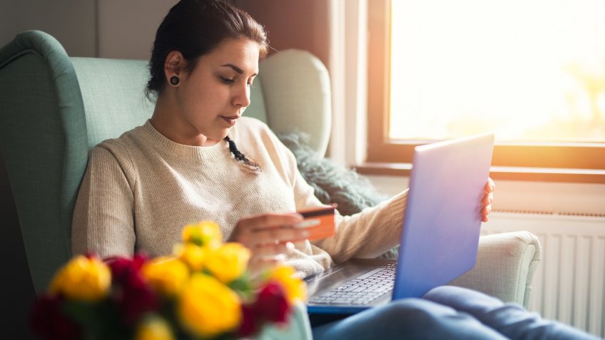 Woman in home shopping online with laptop.
