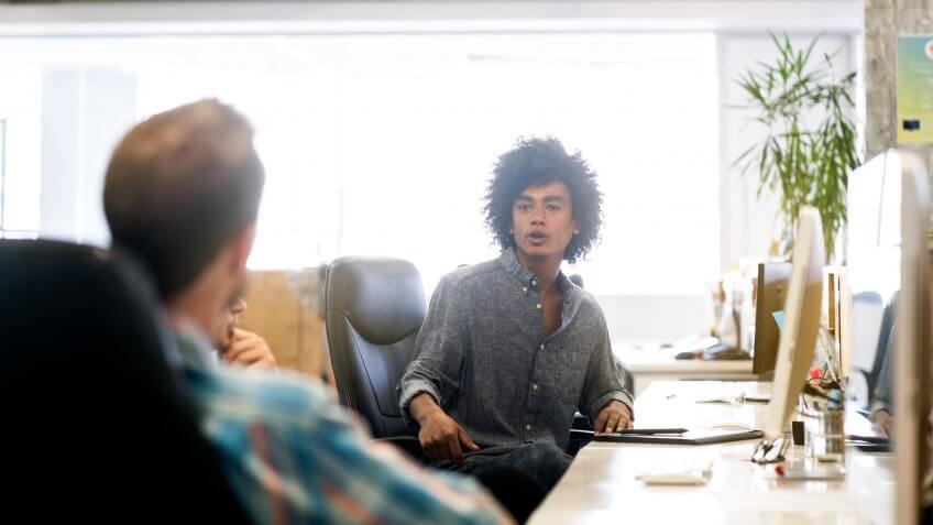 Young businessman talking to colleague in office.