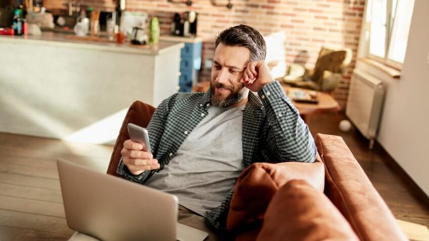 Close up of a young man using a phone at home.
