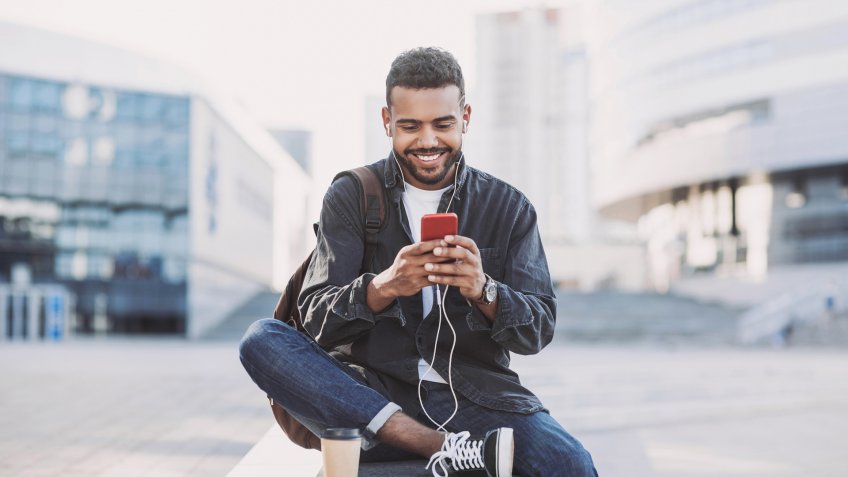 Student men using mobile phone on a city street.