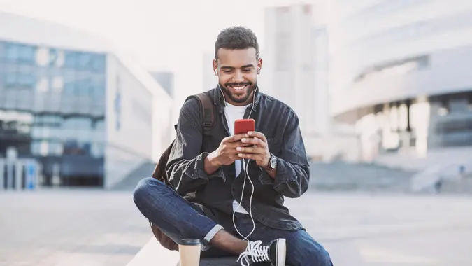 Student men using mobile phone on a city street.