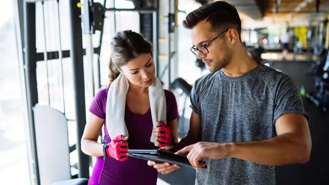 Woman and personal trainer making exercise plan in gym.