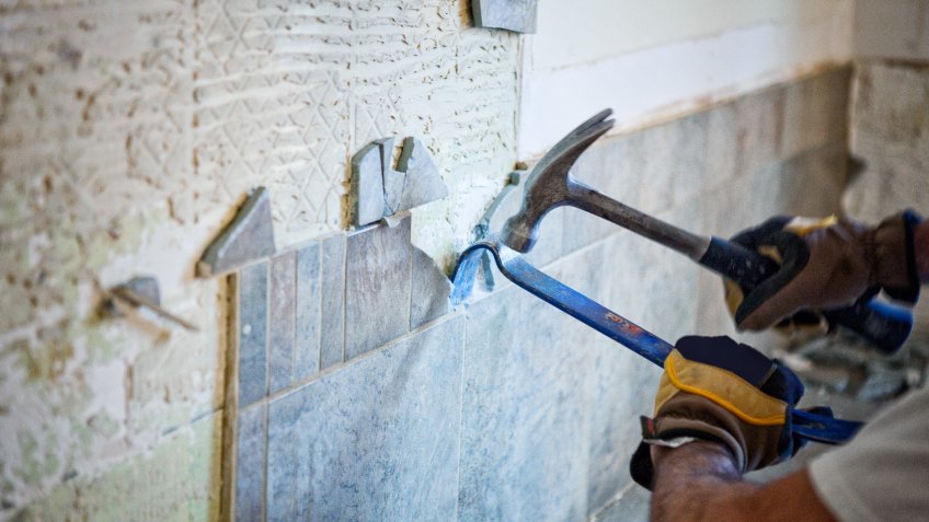 Man removing tile out old kitchen during home renovations.