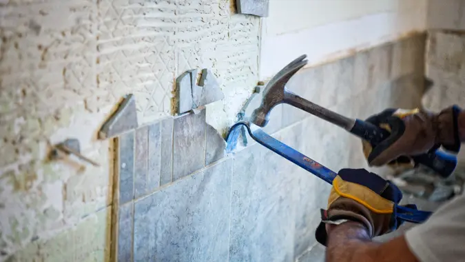 Man removing tile out old kitchen during home renovations.
