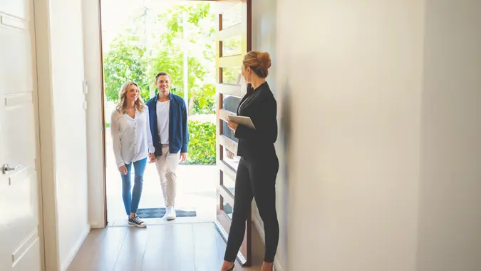 Real estate woman agent showing a happy couple a new house.