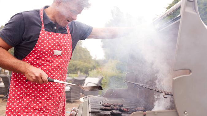 Middle aged man burning food on a barbecue.