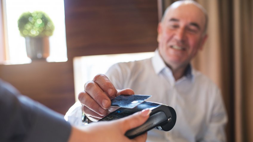 Cheerful senior businessman paying with a credit card.