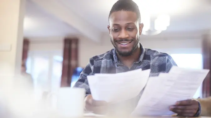 Young black male reading through some paperwork at home.