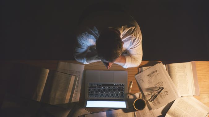 High angle shot of an unrecognizable businessman sitting alone in the office and feeling stressed while working a late night.