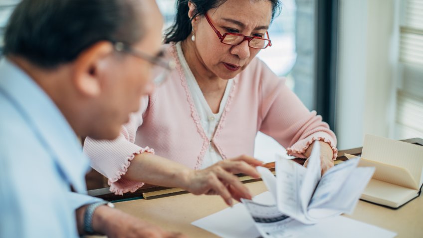 Man and woman, married senior couple calculating finance bills at home.