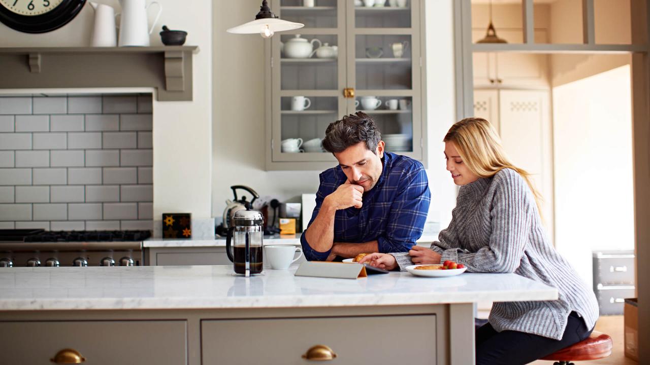 Shot of a young couple using a digital tablet while sitting at their kitchen table at home.