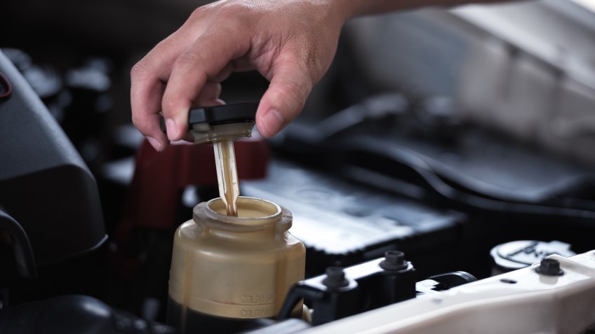 Man hand open power steering cap up for checking level of power steering fluid in the system, car maintenance service concept.