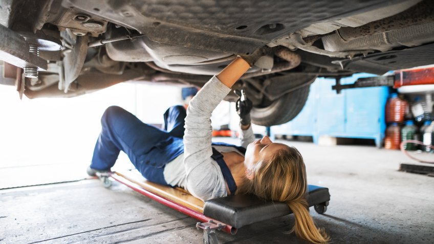 Female mechanic repairing a car.