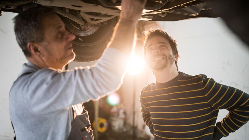 Senior mechanic working at car service,fixing broken car ,talking with client.