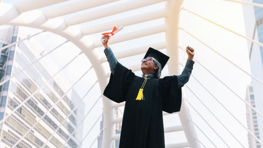 Happy senior adult man in a hat with his gown on graduation day.