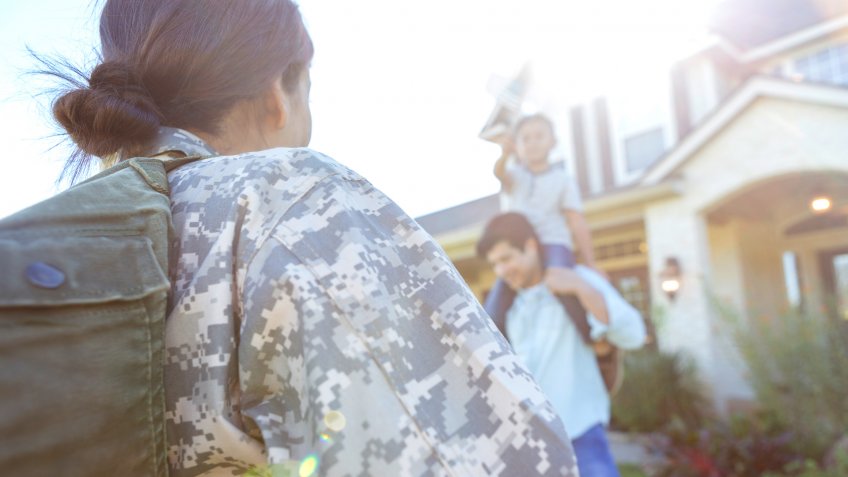 Rear view of mid adult female soldier returning home from military duty.