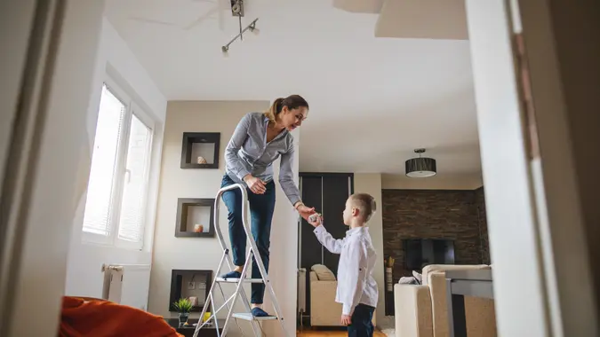 Beautiful mother teaching her young son how to change a light bulb.