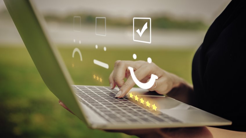 Businesswoman pressing face emoticon on the keyboard laptop / Customer service evaluation concept.