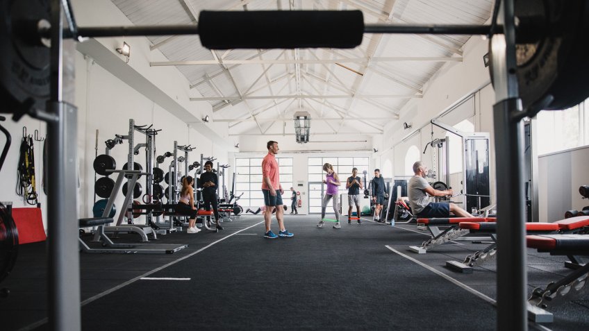 Modern sports gym full of people doing their own workouts.
