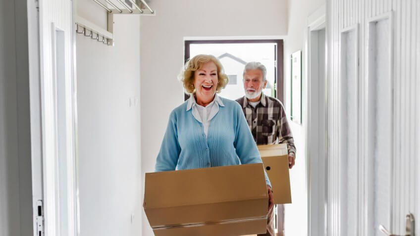 Senior Couple Carrying Boxes Into New Home on Moving Day.