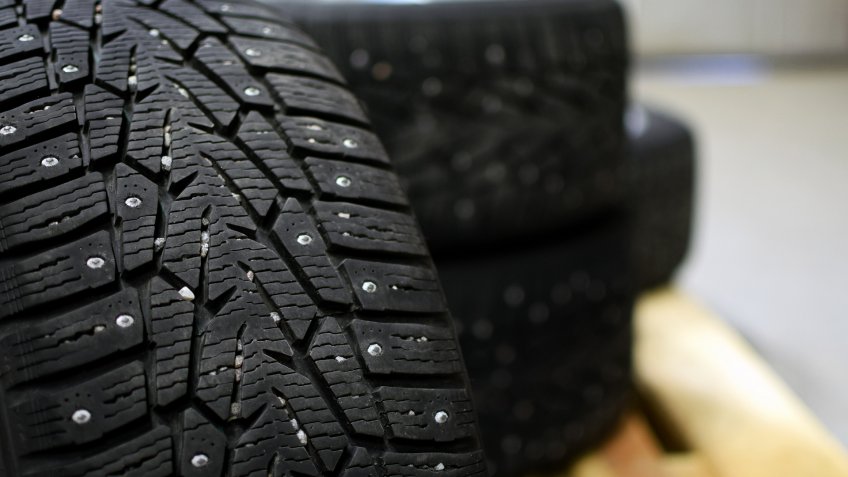 Snow tires with metal studs in garage.