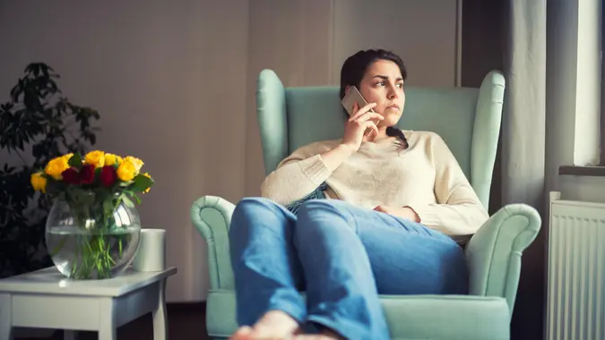 A young woman frowning as she speaks on the phone.