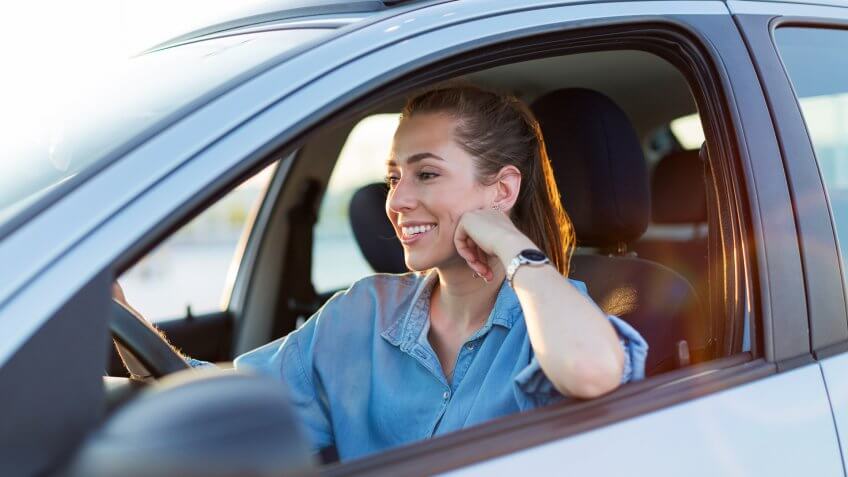Happy woman driving a car and smiling.