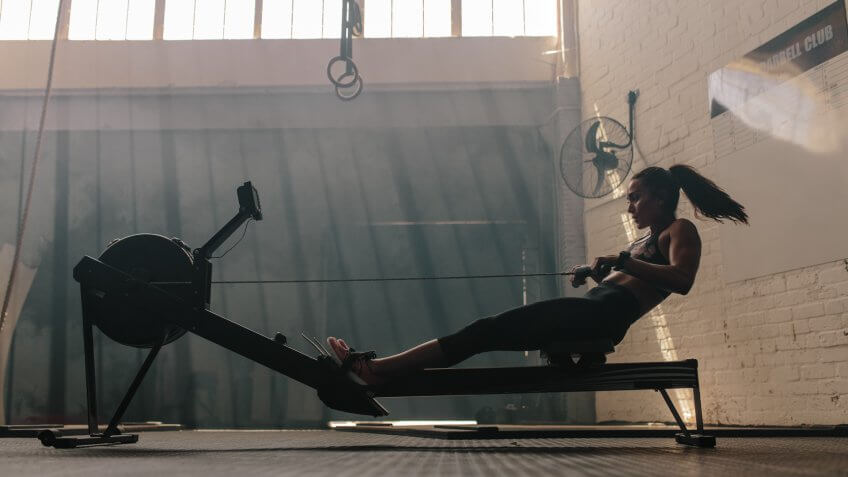 Woman doing cardio workout on rowing machine in the gym.