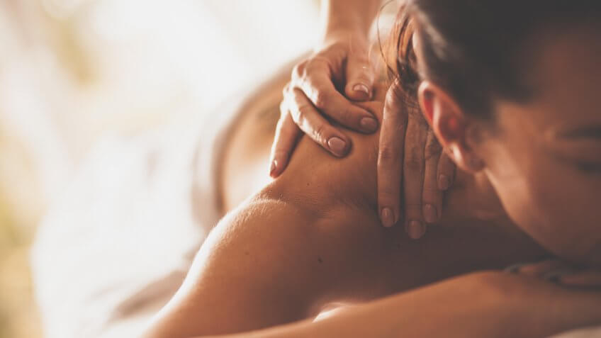 Close-up shot of a woman enjoying relaxing back and shoulder massage at spa.
