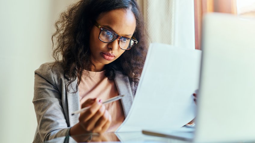 Shot of a young woman going through paperwork at home.