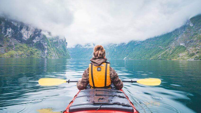 Woman kayaking in Geiranger fjord in Norway.