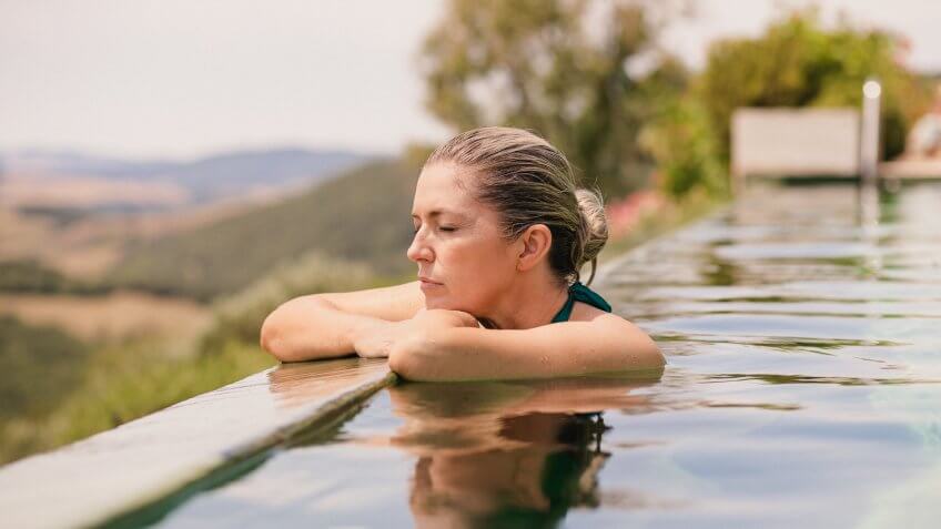 Mature female adult enjoying the sun and relaxing in the pool in Tuscany.