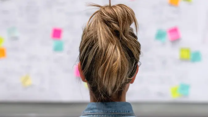 Back of a creative business woman brainstorming at the office using a whiteboard.