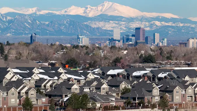 The snow covered Longs Peak and the Rocky Mountains stand behind Downtown Denver skyscrapers, hotels, office and apartment buildings with homes and condos in the foreground.