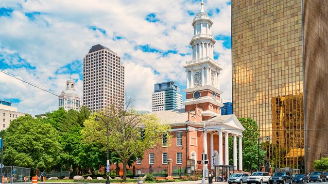 Cars wait at a stop light next to Center Church in downtown Hartford Connecticut on a sunny day.