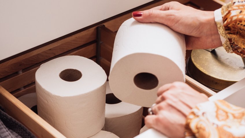 Toilet paper storage in bathroom drawerPhoto of female hand grabbing a new roll.