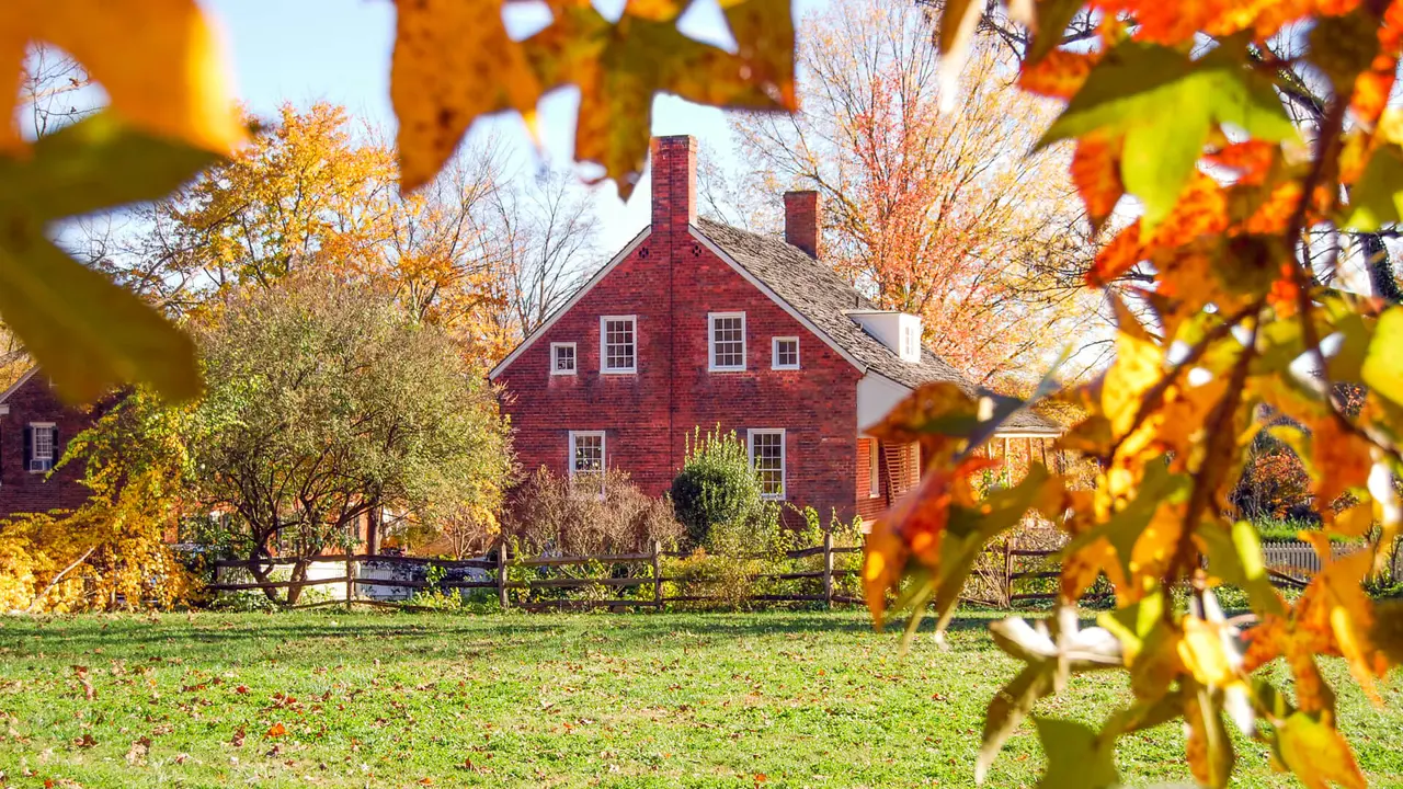 "Brown House framed by color changing leaves.