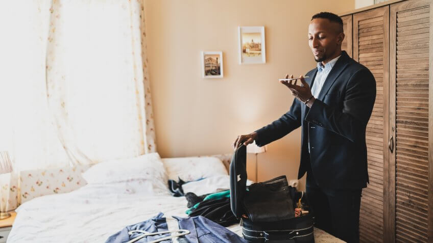 Businessman prepares his clothes in suitcase on bed.