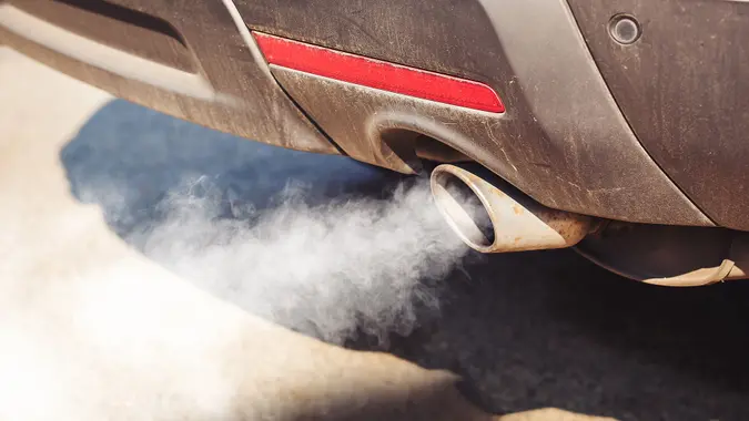 air pollution from dirty and aged vehicle exhaust pipe on road.