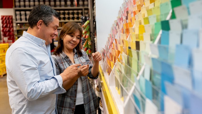 Portrait of a loving couple at hardware store choosing a color to paint their house and holding a palette - decoration concepts.