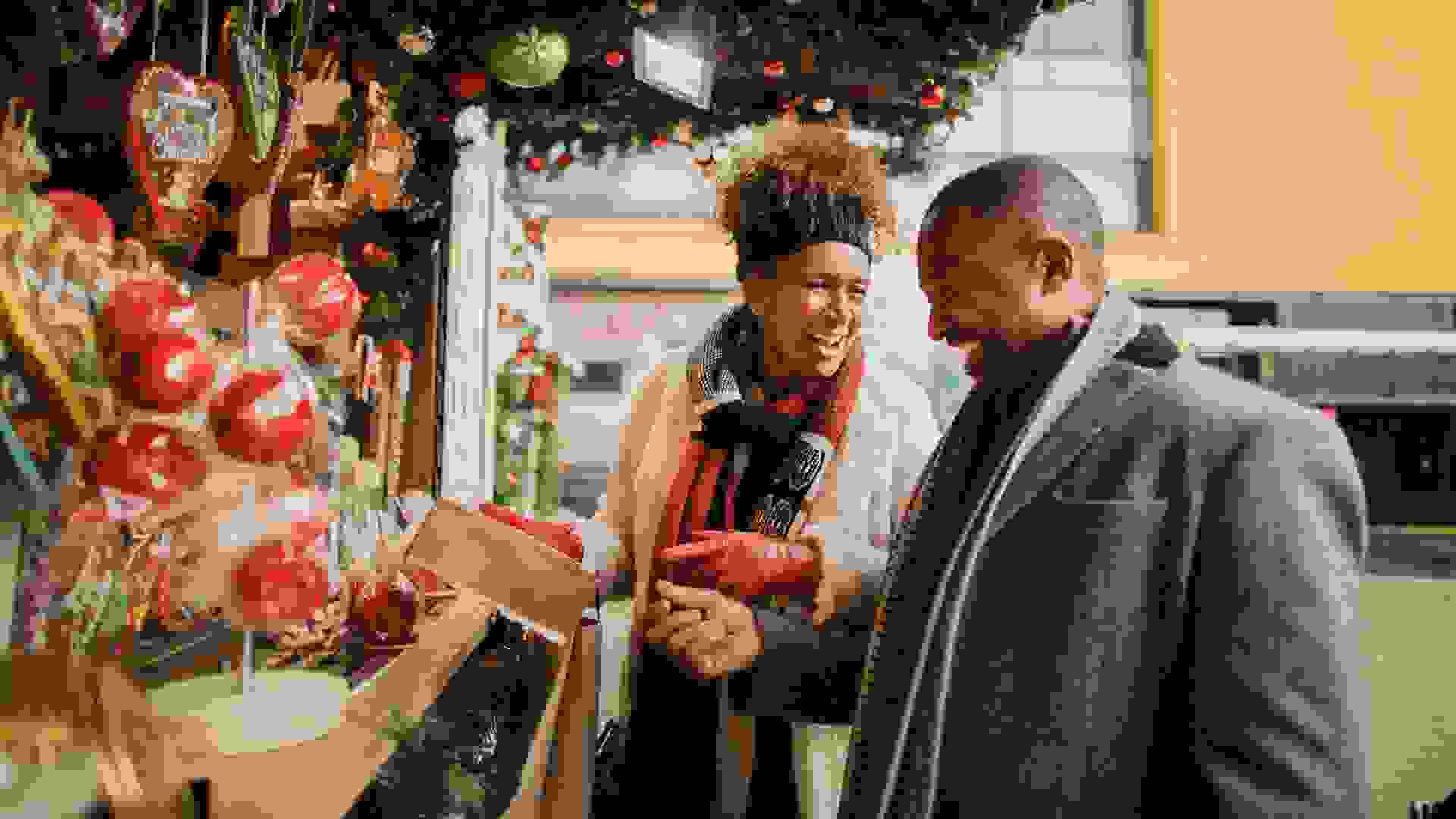 Mature couple looking at a Christmas market stall in a city centre.