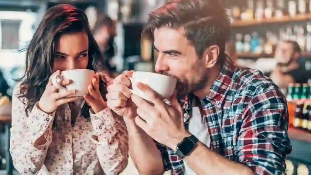 Beautiful young couple drinking coffee and looking each other.