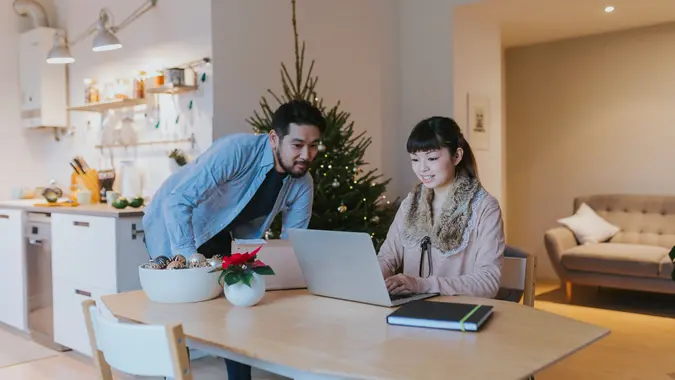 Happy Japanese couple at home, having video conference call with the parents.