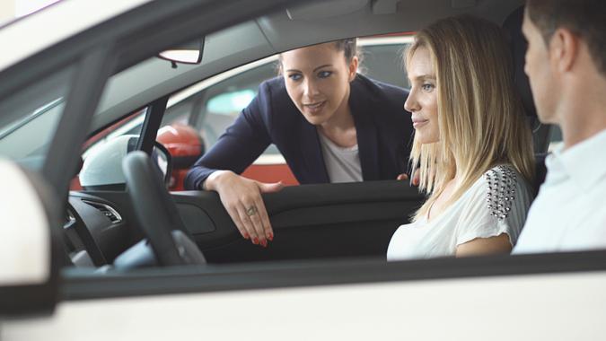 Closeup side view of mid adult couple sitting in a brand new car at a local dealership.