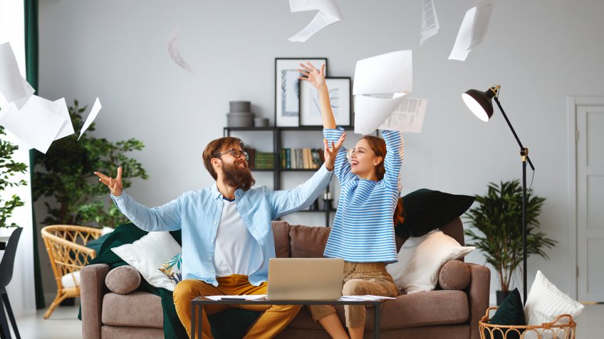 married couple with bills receipts documents and a laptop at home.