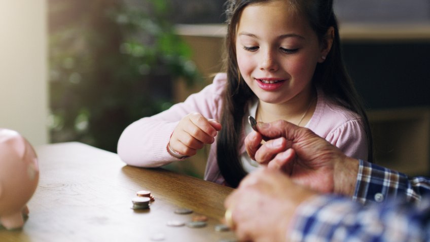 Shot of a little girl learning about money from her grandfather.