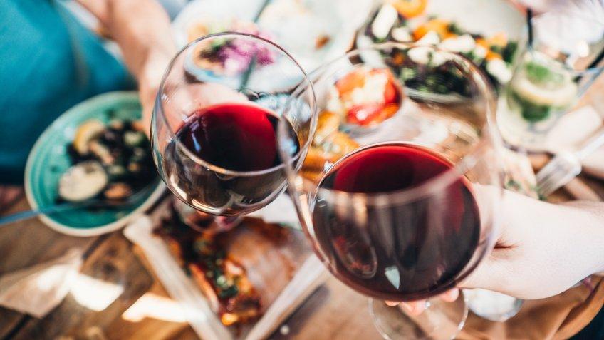 Close up of a friends toasting with red wine at restaurant.
