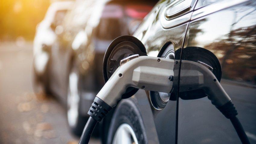 Electric car charging on parking lot with electric car charging station on city street.
